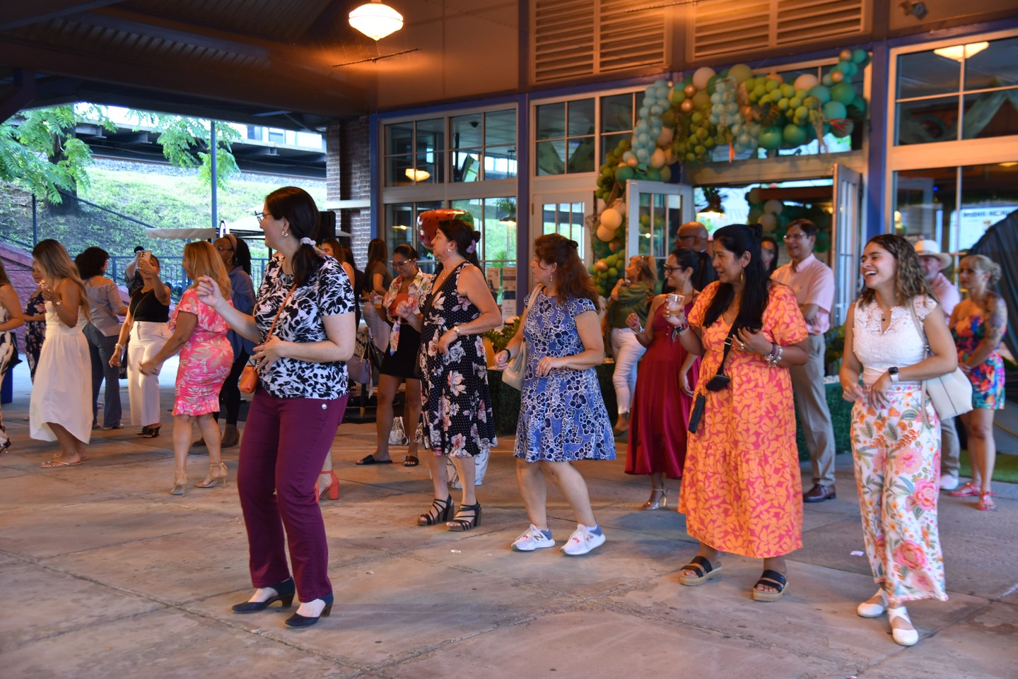 Guests indoors under the Welcome to Salsa and Networking screen beside a balloon arch