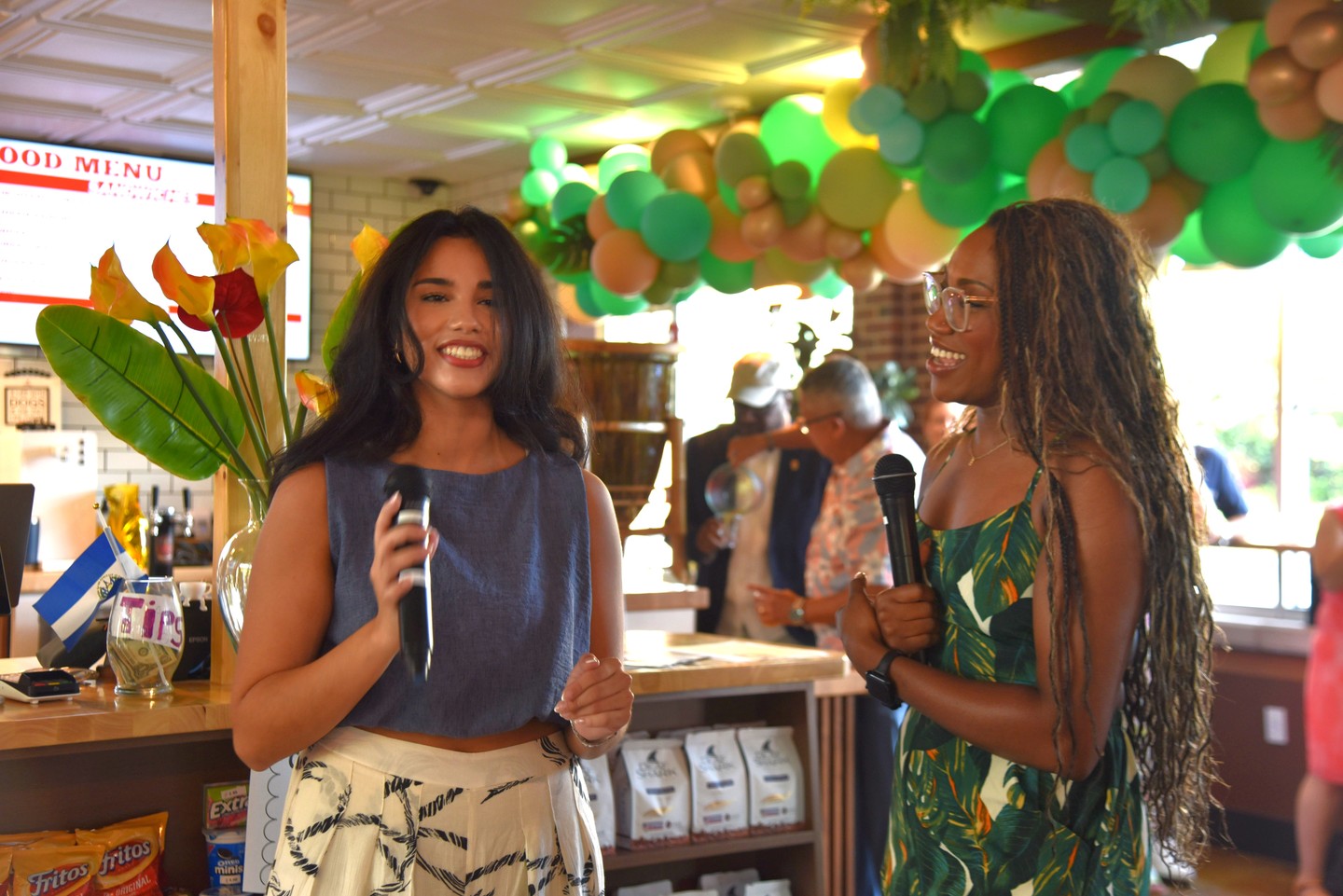Two hosts speaking with microphones by the counter